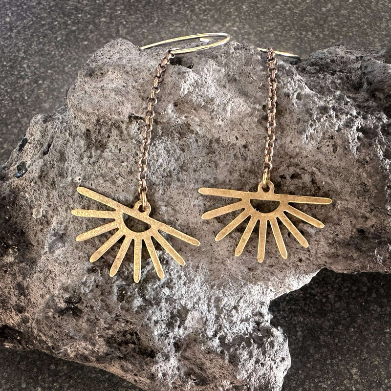 Sunbeam Earrings with delicate beams of light showcased on textured rock background.