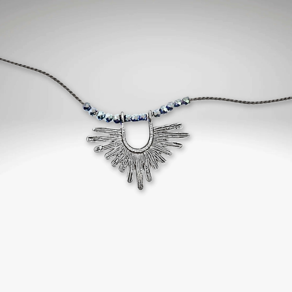 Sunbeam Necklace featuring a striking geometric pendant on a delicate silk cord with small hematite beads.