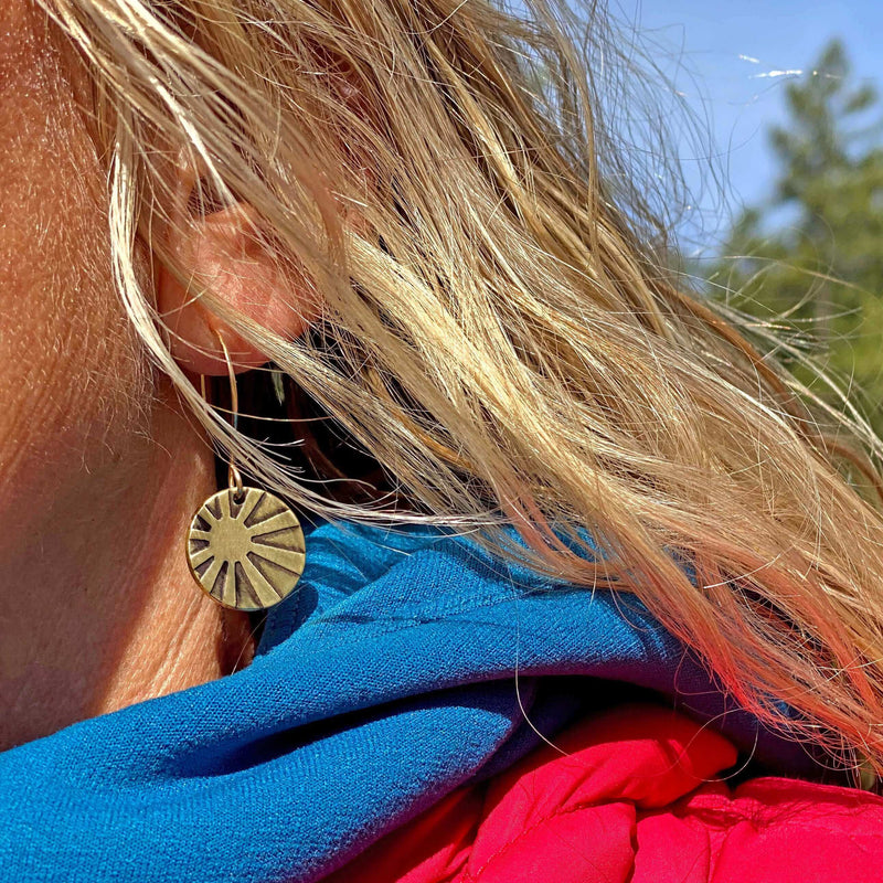Close-up of a woman wearing Mini Sun Ray Hoop Earrings with a colorful scarf, showcasing the intricate etched design.