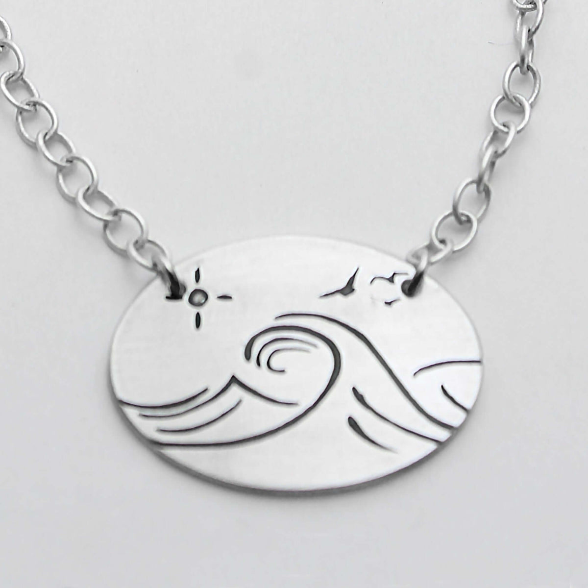 Swell Necklace features wave etching on matte silver pendant with an adjustable cable chain.