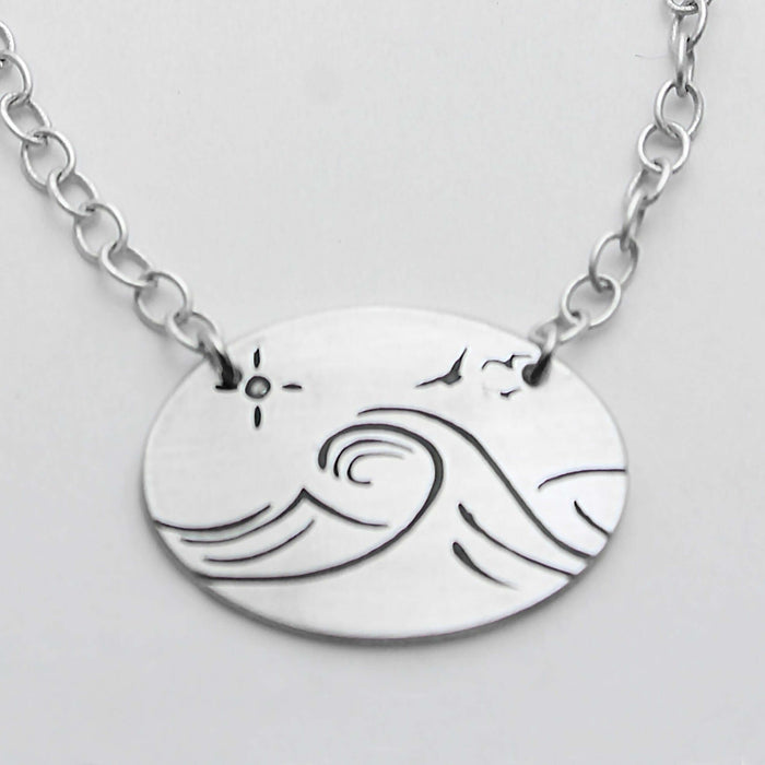 Swell Necklace features wave etching on matte silver pendant with an adjustable cable chain.