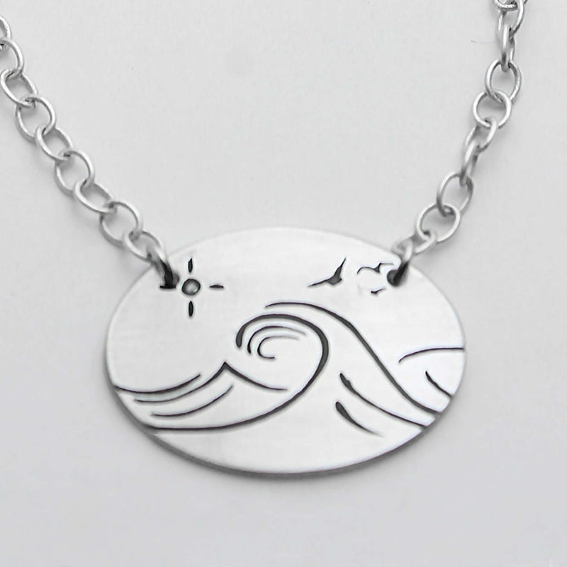 Swell Necklace features wave etching on matte silver pendant with an adjustable cable chain.