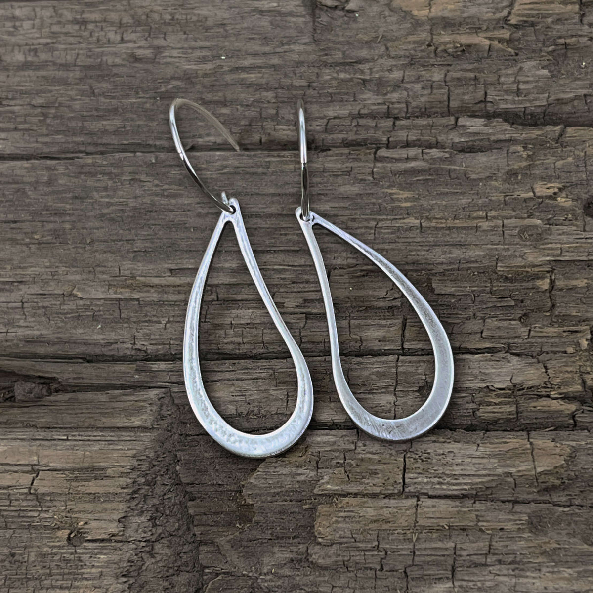 Teardrop Earrings made of solid brass featuring an open asymmetrical design in matte silver finish.