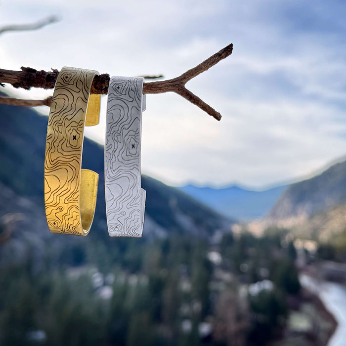 Topo Cuff Bracelet - Mountain cuff for men and women - Grand Tetons displayed outdoors on a branch with a scenic mountain backdrop.