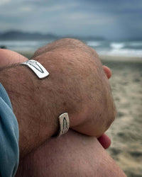 Trout on Tips Cuff Bracelet worn on wrist at the beach, showcasing nature-inspired design.