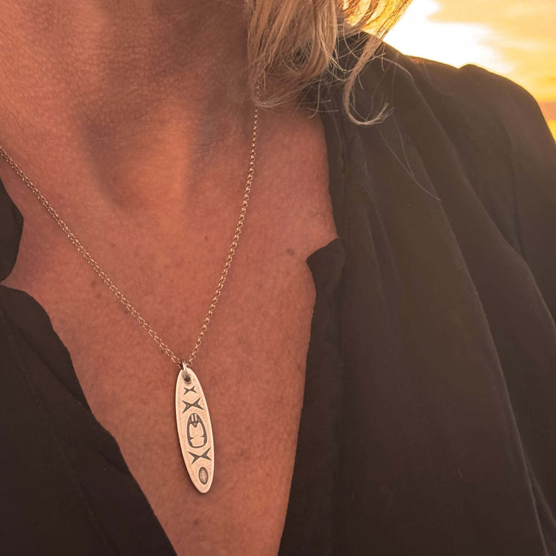 Close-up of the Upstream Necklace with delicate kayak design worn on a woman, showcasing its beauty during sunset.