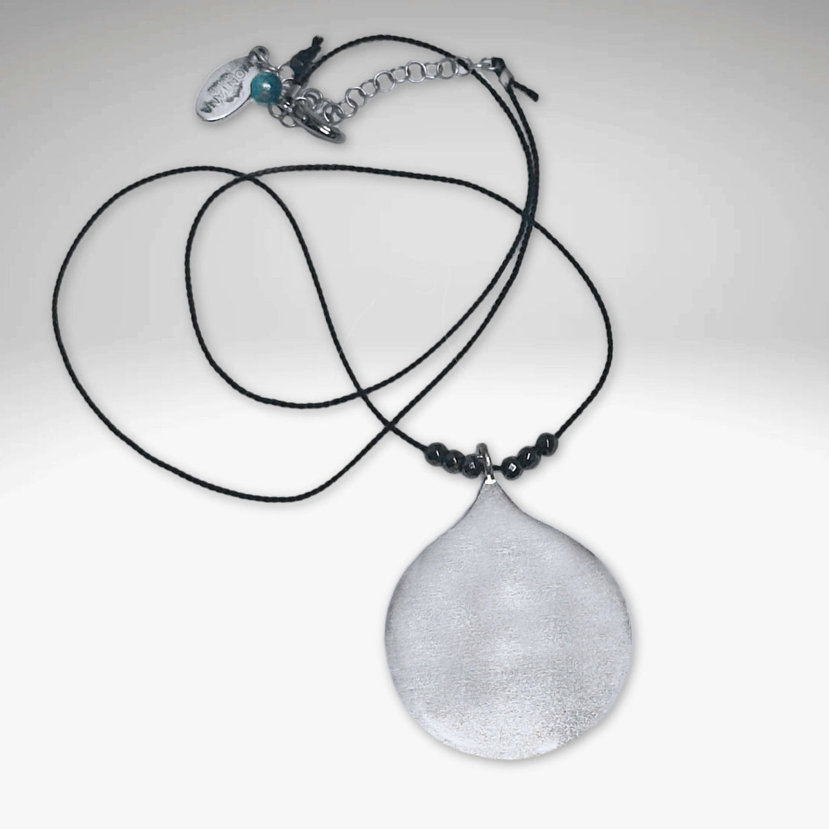 Waterdrop Necklace featuring a hammered pendant on a delicate silk cord with hematite beads.