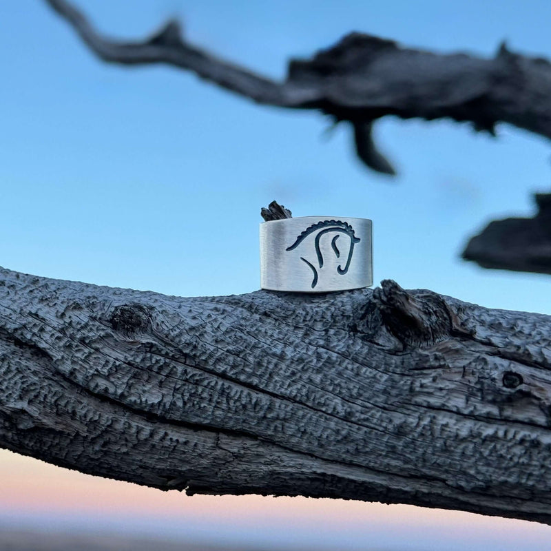 White Horse Adjustable Ring resting on a tree branch, showcasing a dressage horse silhouette.
