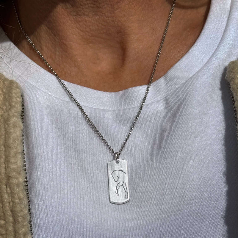White Horse Necklace displayed on a model, featuring a unique etched design on raw brass with a dainty chain.