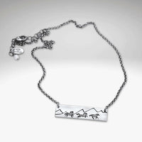 Wild Horses Necklace featuring a mountain and mustangs design, etched in silver with a stylish chain.