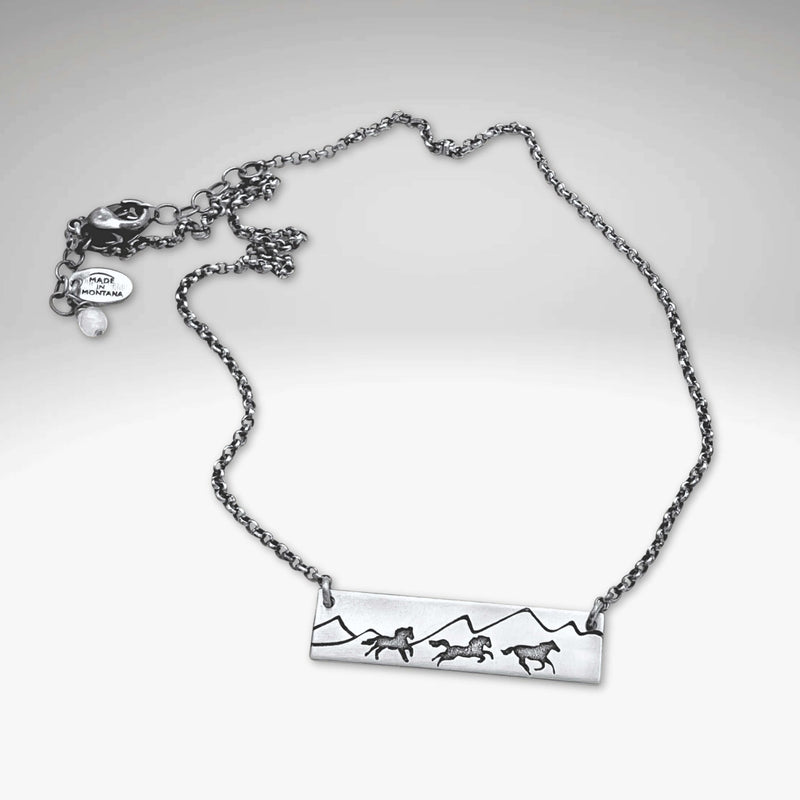 Wild Horses Necklace featuring a mountain and mustangs design, etched in silver with a stylish chain.