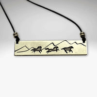Wild Horses Necklace showcasing etched brass design with running horses and mountains on a strap.