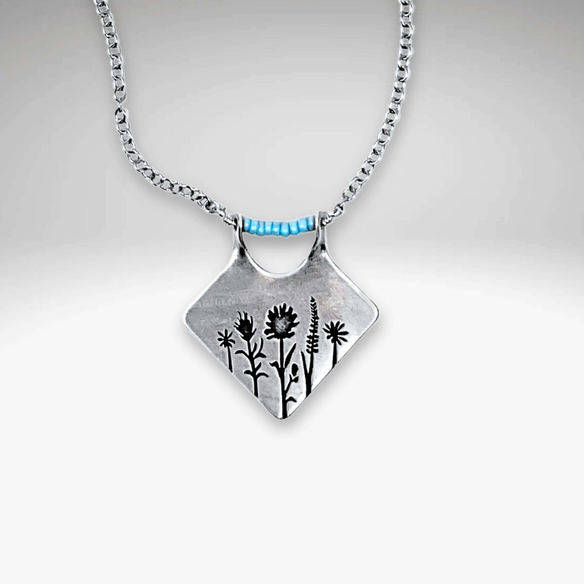 Wildflower Box Necklace featuring intricate floral design and matte silver finish, perfect for celebrating new beginnings.