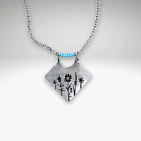 Wildflower Box Necklace featuring intricate floral design and matte silver finish, perfect for celebrating new beginnings.