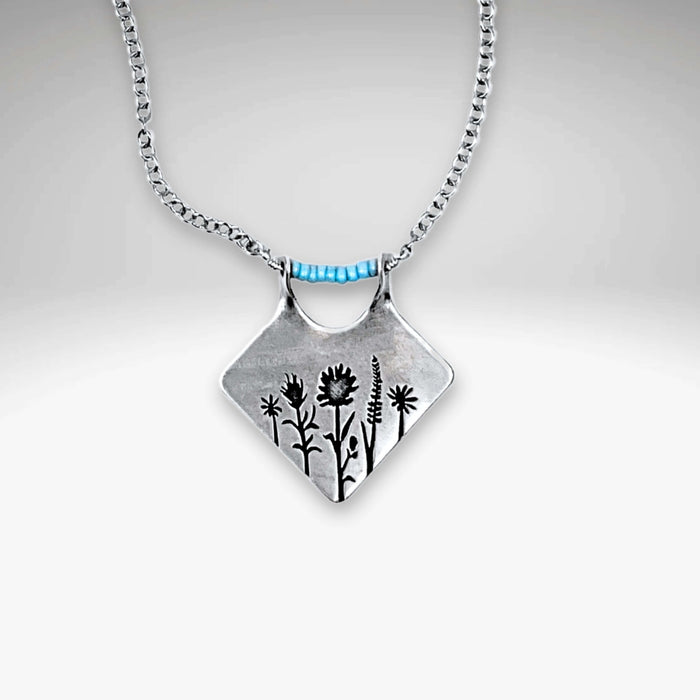 Wildflower Box Necklace featuring intricate floral design and matte silver finish, perfect for celebrating new beginnings.