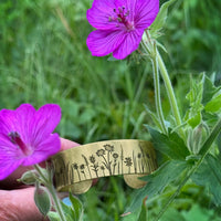 Wildflower Field Cuff displayed among vibrant pink wildflowers in a lush green field.