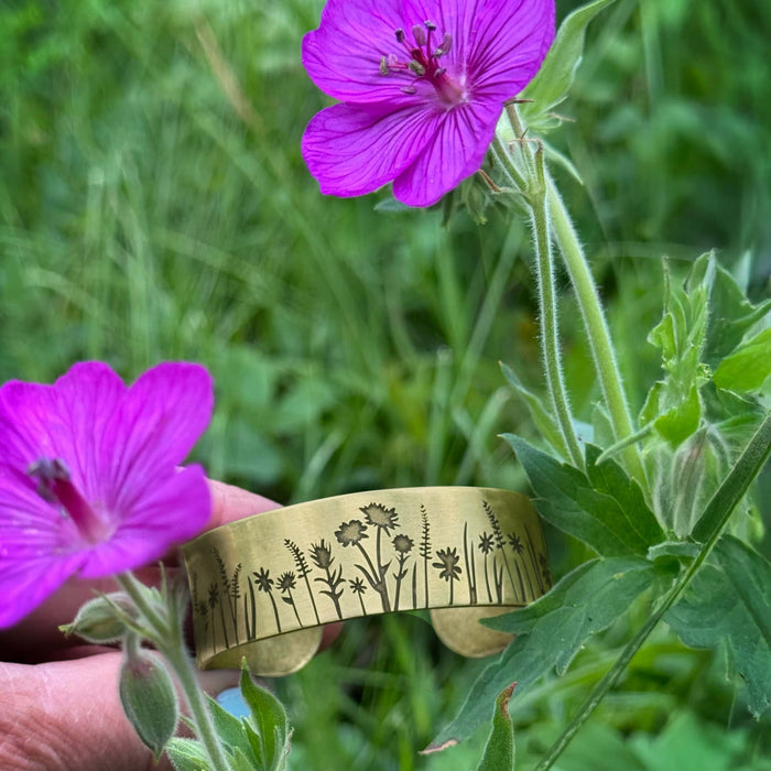 Wildflower Field Cuff displayed among vibrant pink wildflowers in a lush green field.