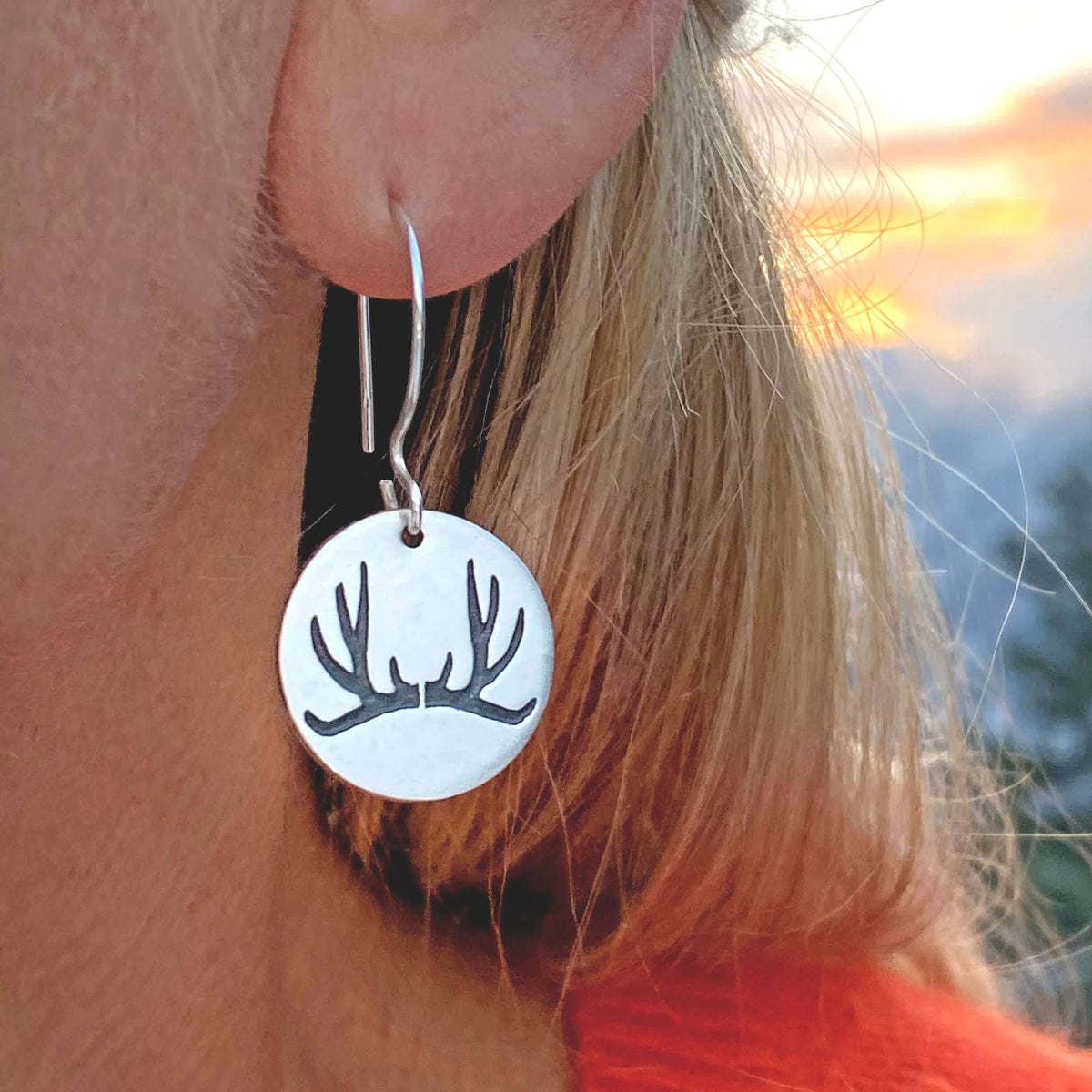 Close-up of a person wearing Antler Earrings made from solid brass with a silver finish, featuring etched antler design.