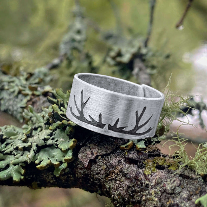 Antlers Adjustable Ring displayed on a tree branch with moss, showcasing its nature-inspired design.
