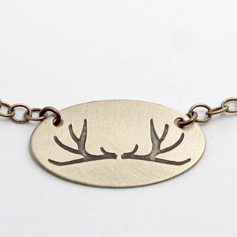 Antlers Necklace featuring a simple etched oval design with antlers, suitable for nature lovers and hunters.