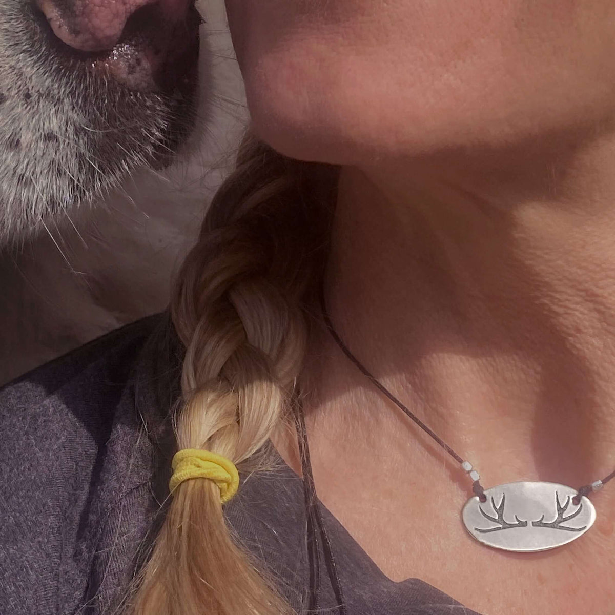 Antlers Necklace worn by a woman with a dog, showcasing its elegant oval shape and nature-inspired design.