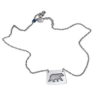 Bear Boy Necklace featuring a black bear charm on an asymmetrical rectangle, displayed on a simple chain.