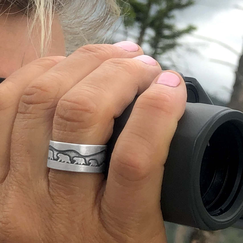 Bears on a Hike Adjustable Ring worn by a person holding binoculars, showcasing wildlife jewelry in nature.