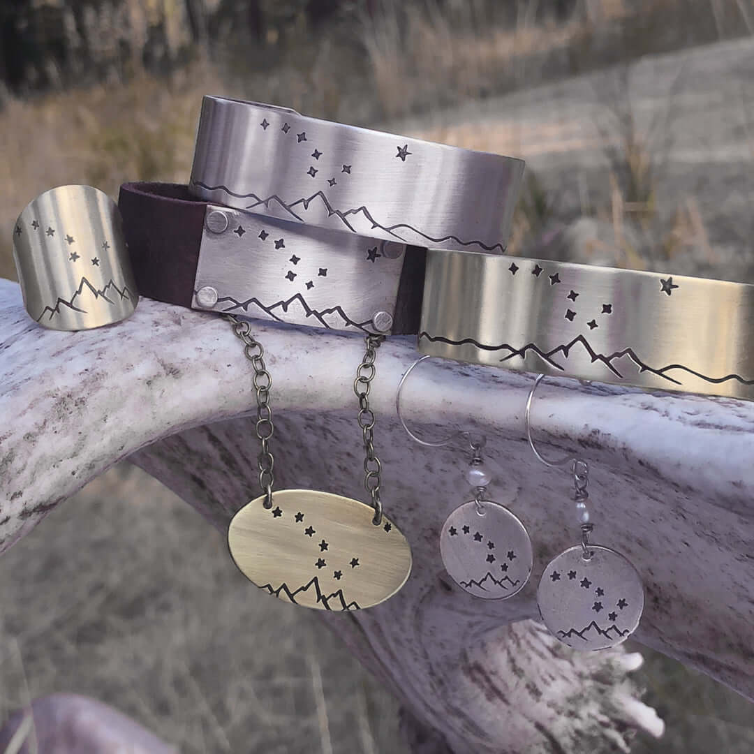 Big Dipper Cuff Bracelet with mountain and star etching, showcasing unique designs in a natural outdoor setting.