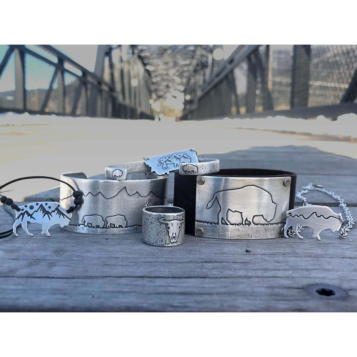 Bison Skull Ring and other nature-themed jewelry displayed on a wooden surface outdoors.