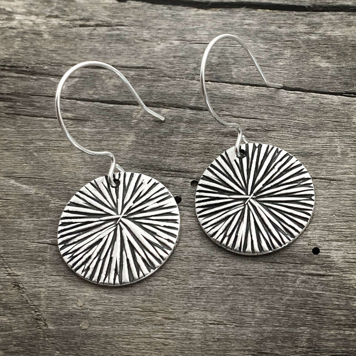Stylish Blossom Earrings featuring a modern blossom design with a matte silver finish on a rustic wooden background.