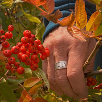 Buff Adjustable Ring worn on a hand surrounded by vibrant autumn leaves and red berries.