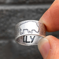 Buffalo Ring with etched bison design viewed in hand against a textured background.