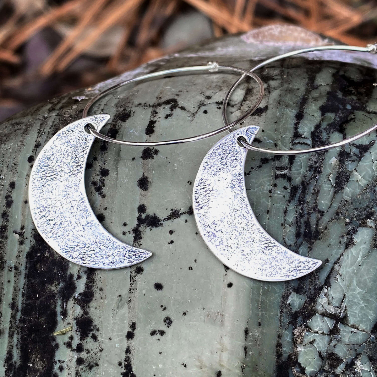 Crescent Moon Hoop Earrings detailed image showcasing solid brass and hammered texture on the moons, set on a natural stone.