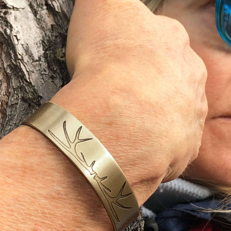 Elk Antlers Cuff Bracelet worn on a wrist, featuring intricate elk antler etching in Antique Brass finish.