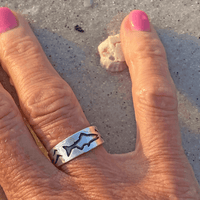 Fishing Adjustable Ring shown on a hand, featuring etched fish designs and a matte silver finish.