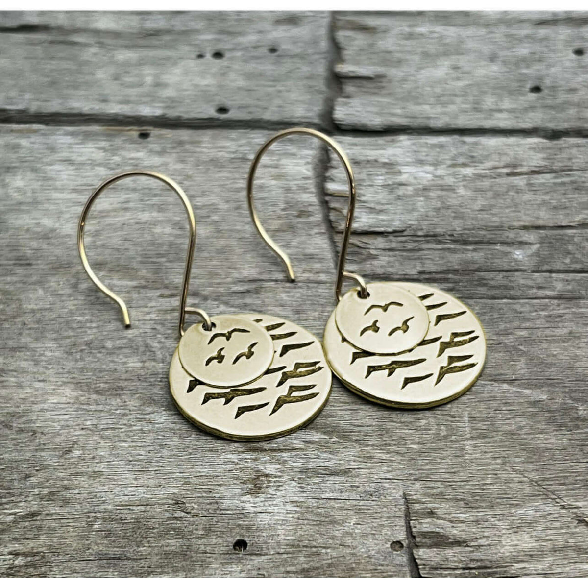 Flyover Earrings featuring two stylish gold disks with bird designs, evoking coastal charm.