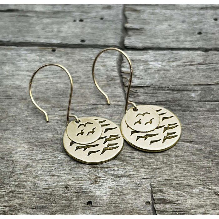 Flyover Earrings featuring two stylish gold disks with bird designs, evoking coastal charm.