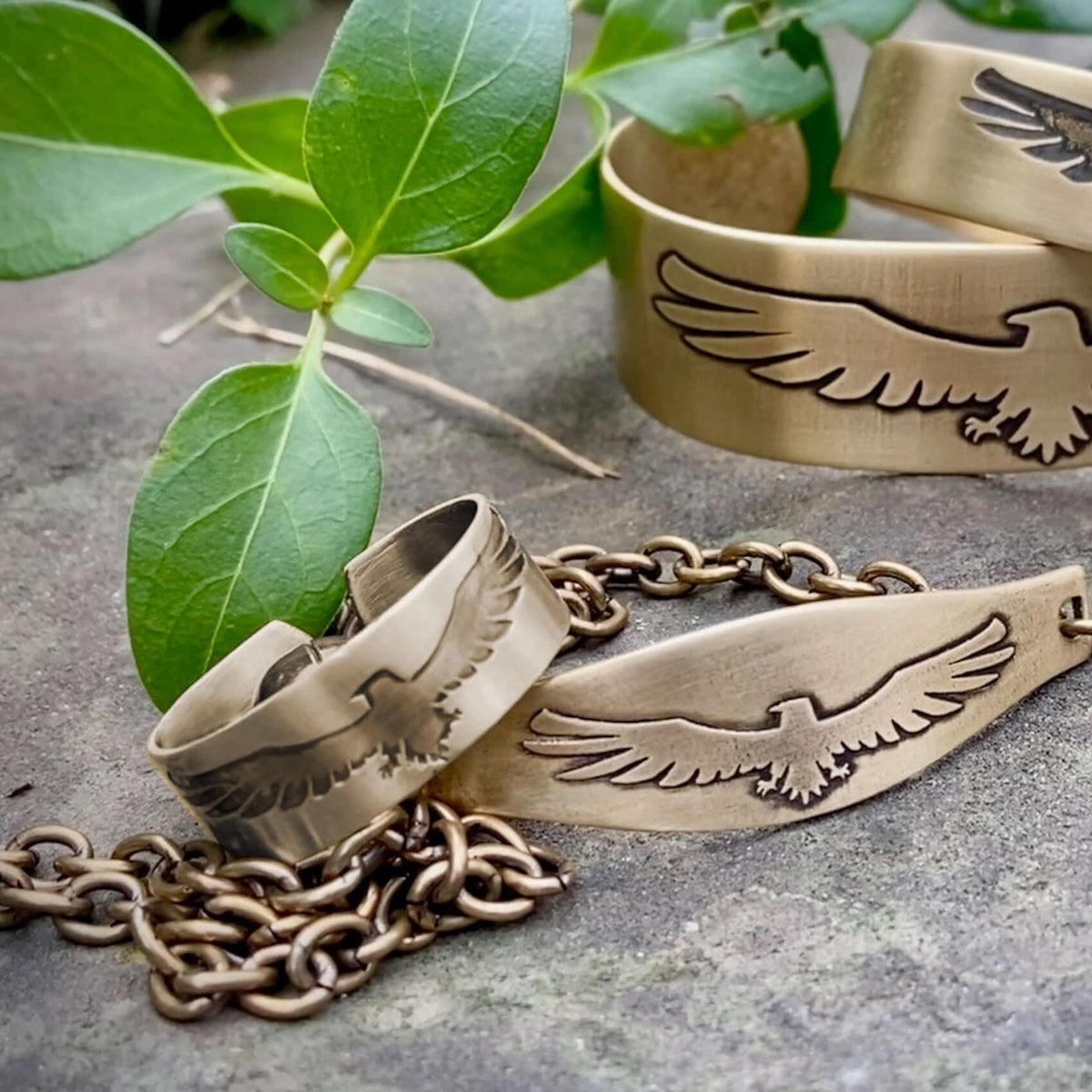 Freebird Adjustable Ring in Antique Brass with eagle motif, surrounded by greenery.