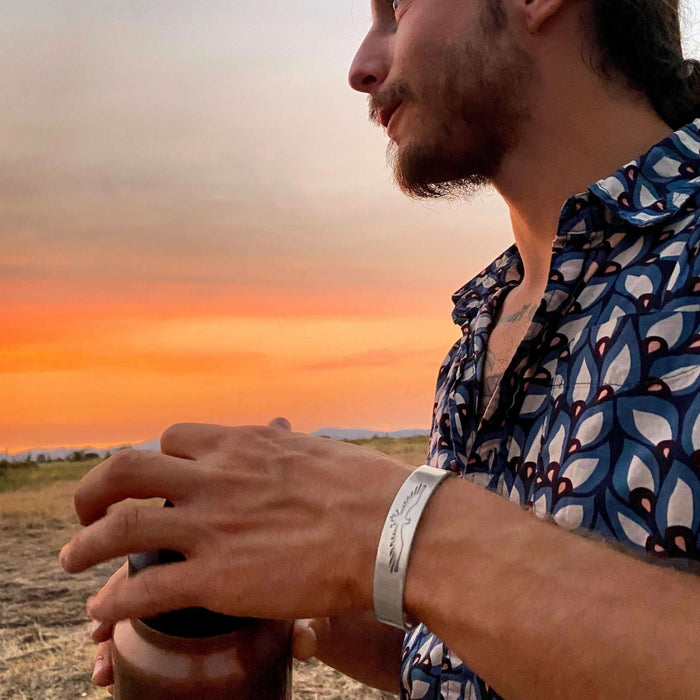 Freebird Cuff Bracelet- Eagle Bird bracelet for men and women worn by a man against a sunset background.