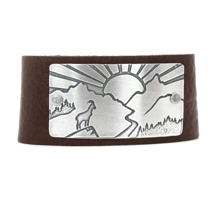 Going to the Sun Road Leather Cuff featuring mountain goat etching and sun design, crafted from leather and metal.