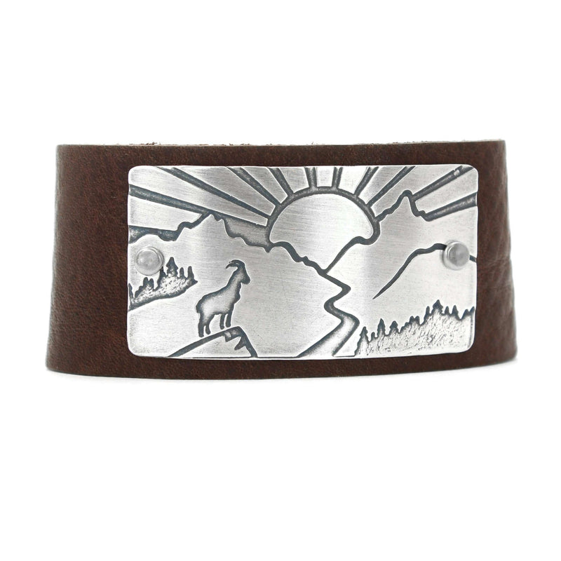 Going to the Sun Road Leather Cuff featuring mountain goat etching and sun design, crafted from leather and metal.