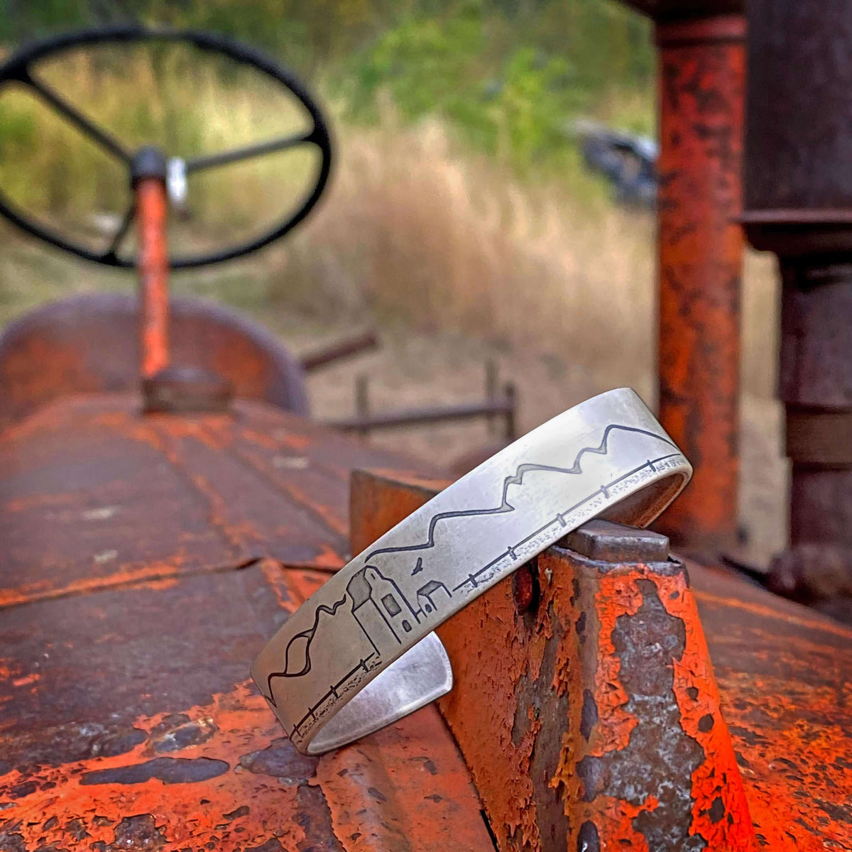 Grain Elevator On the Front Cuff Bracelet resting on an orange vintage tractor, showcasing deep engraving and unique design.