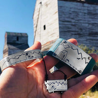 Grain Elevator On the Front Cuff Bracelet displayed with a hand, featuring deep engravings and landscape details.