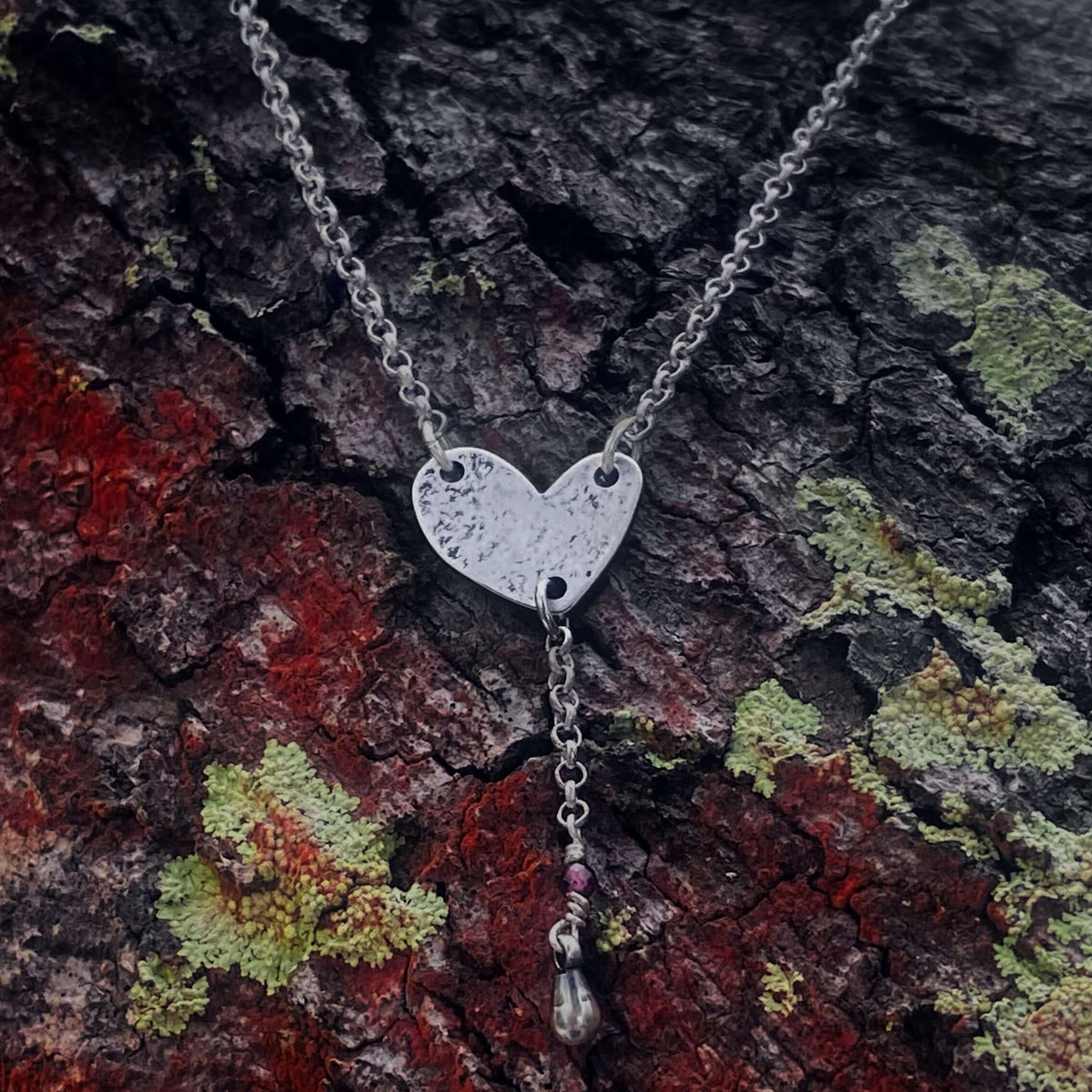 Heart Throb Y Necklace on textured bark background, symbolizing love and memories.
