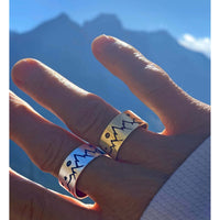 High Alpine Adjustable Ring showcased on hand against mountain backdrop in silver and brass finishes.