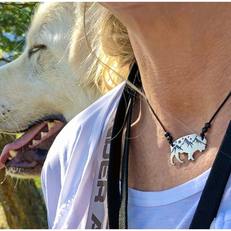 High Alpine Bison Necklace worn by woman outdoors, featuring mountains and bison design on a black cord.