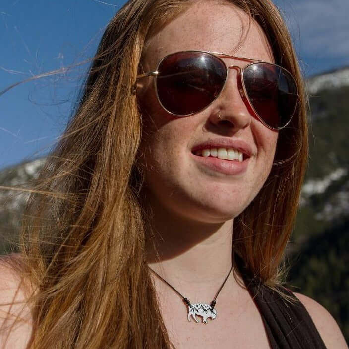 Woman wearing High Alpine Bison Necklace, enjoying nature with mountains in the background.