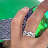 High Alpine Mountain Ring worn on a hand against a green backdrop, showcasing mountain and star design.