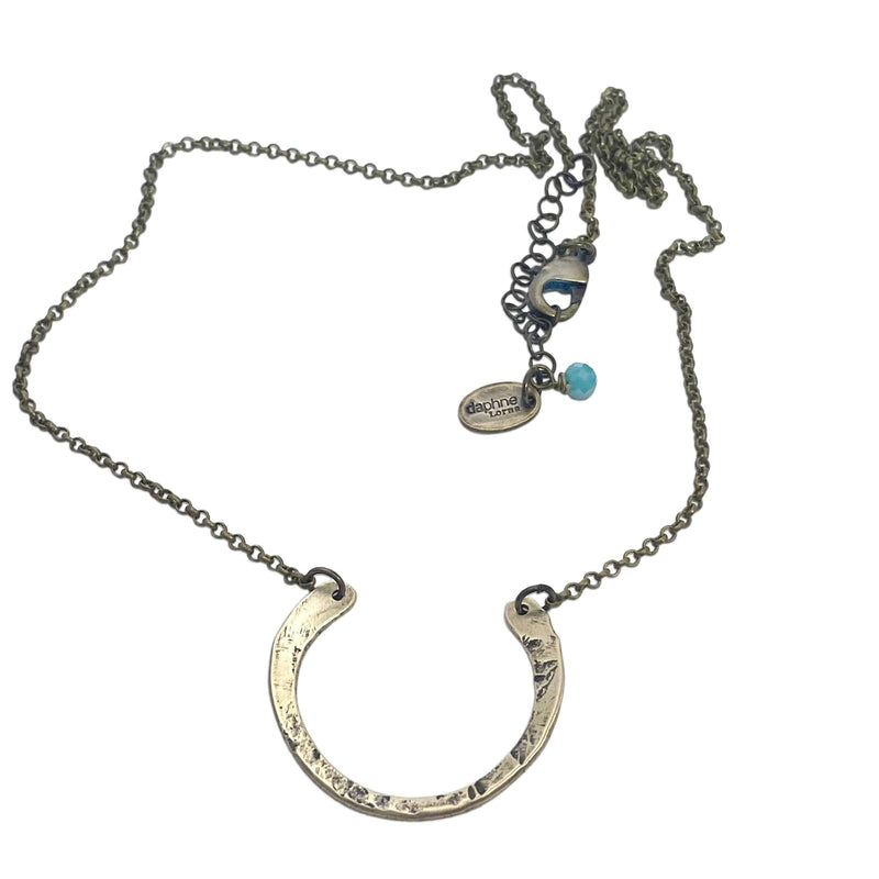 Elegant horseshoe necklace with a hammered finish on a delicate rolo chain, perfect for everyday wear.