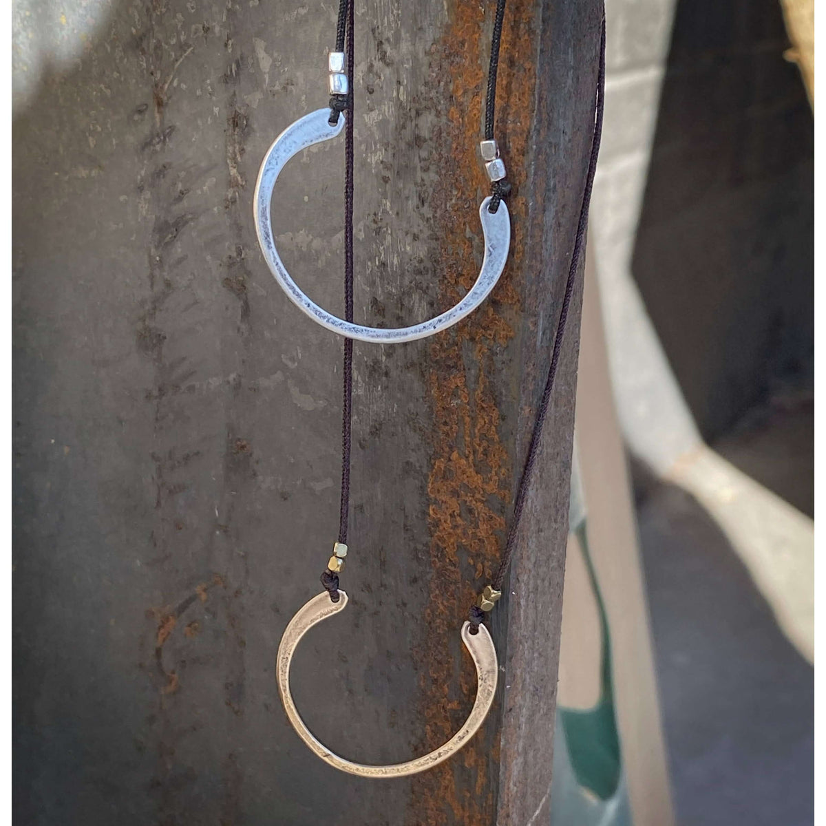 Horseshoe Necklace with semi-circle pendants in silver and gold, hung on black cords